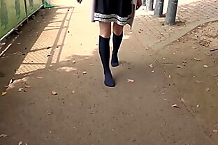 A girl walks on a dirt or sandy road with just socks without wearing shoes